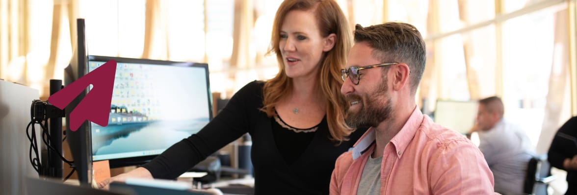 Two people looking at a double computer monitor