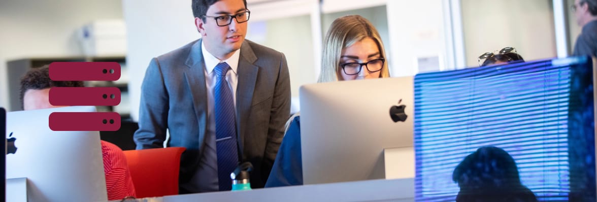 Two people working in an office and looking at a computer monitor