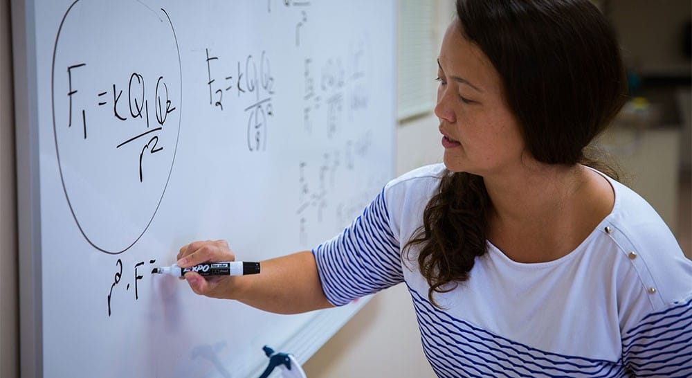 Woman writing an equation on a white board