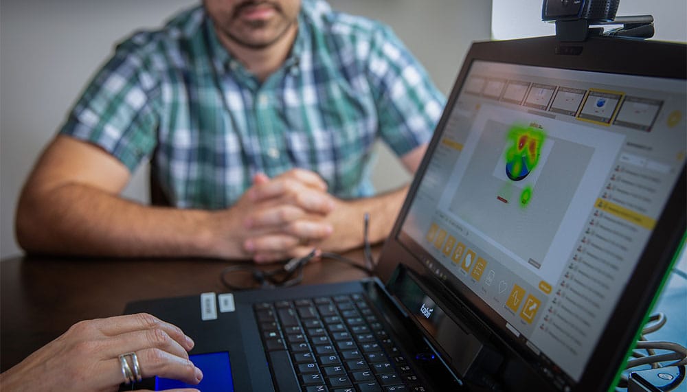 People sitting at a desk looking at an image on a laptop