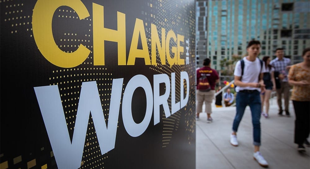 Student walking by a sign that says 'change the world'