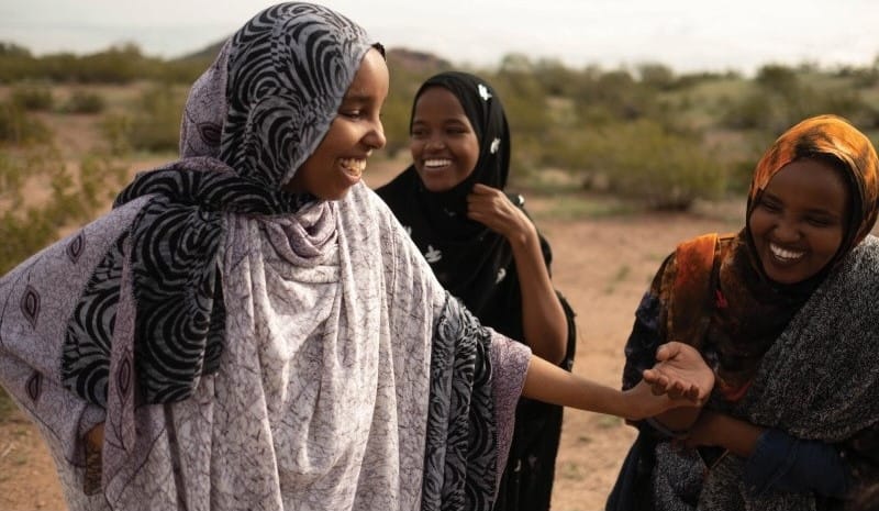 Women laughing together and wearing headscarves