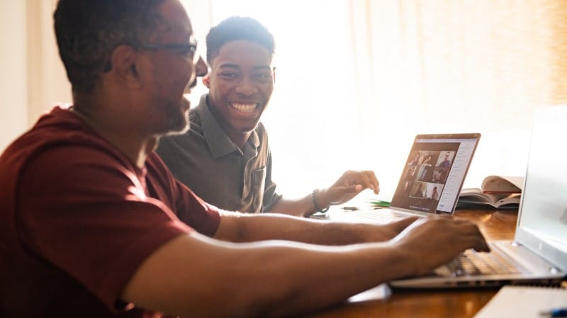 Son and dad sitting at home on laptops